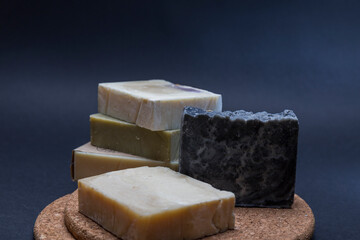 set of handmade soaps, soaps forming a tower on a cork surface and a black background