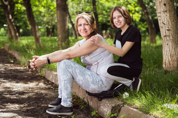 In the park, a woman and her teenage daughter communicate, spend time together, discuss teenage problems, learning difficulties, relationships with boys