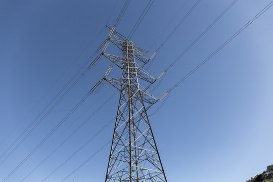metallic electrical tower with parallel cables divides the blue sky