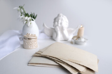 first spring flowers, snowdrop, Galanthus in vase, an angel figurine, stack of vintage photos, candle is lit, concept of family tree, genealogy, memory of ancestors