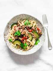 Spicy noodles with beef, sweet pepper and zucchini - a delicious lunch on a light background, top view