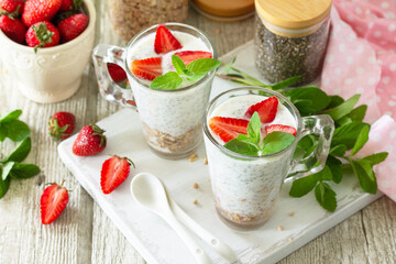 Healthy eating concept breakfast. Homemade granola with strawberry, yogurt, chia seeds, homemade granola and fresh berries on a wooden table.