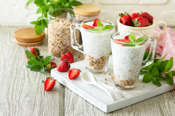 Healthy eating concept breakfast. Homemade granola with strawberry, yogurt, chia seeds, homemade granola and fresh berries on a wooden table. Copy space.