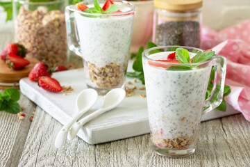 Healthy eating concept breakfast. Homemade granola with strawberry, yogurt, chia seeds, homemade granola and fresh berries on a wooden table.