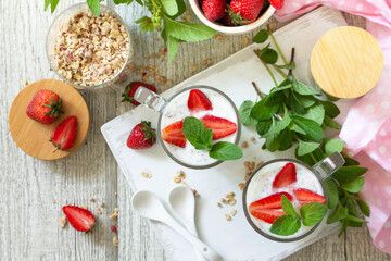 Healthy eating concept breakfast. Homemade granola with strawberry, yogurt, chia seeds, homemade granola and fresh berries on a wooden table. Top view flat lay.