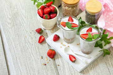 Healthy eating concept breakfast. Homemade granola with strawberry, yogurt, chia seeds, homemade granola and fresh berries on a wooden table. Copy space.