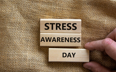 Stress awareness day symbol. Wooden blocks with words 'Stress awareness day'. Beautiful canvas background. Doctor hand. Psychological, business and stress awareness day concept. Copy space.