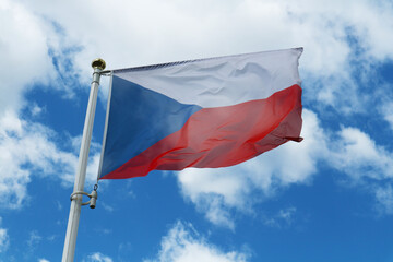 The flag of the Czech Republic against the blue sky near the multi-storey residential building.