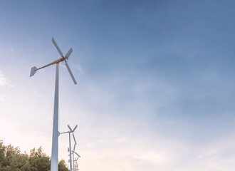 White small wind turbine at sun rise time, windmill farm sustainable renewable energy source of future.