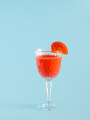 a glass of red juice tomato with tropical tomato on blue pastel background. creative decoration idea. minimal background