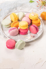 Colorful french macaroon cakes. Macaroons with jasmine flowers on white table background. Selective focus