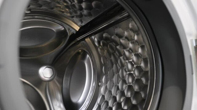 The camera slowly moves along the open washing machine and shows its interior