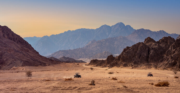 Desert safari in Sharm-el-Sheikh, Egypt. Buggy trip in a stone desert with silhouettes of mountain hills at sunset. 