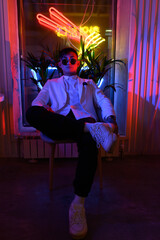 young Asian man in a white suit on a background of neon lights