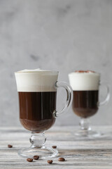 Obraz na płótnie Canvas Two glass glasses with handles with Irish coffee with coffee beans on a wooden table