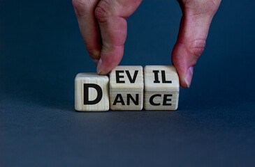 Dance with the devil symbol. Hand turns cubes and changes the word 'dance' to 'devil'. Beautiful grey background. Business and dance with devil immoral concept. Copy space.