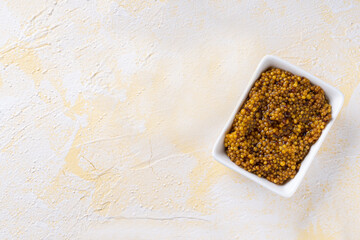 Closeup of french mustard with whole seeds on yellow cement background