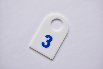 Clothing tag with number three on a white background