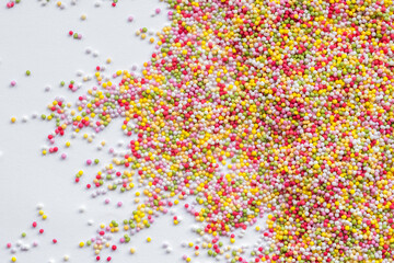 Rainbow ball-shaped sprinkles used as a topping for cakes on white background