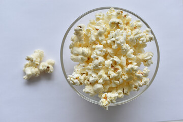 Glass saucer with popcorn on a white background