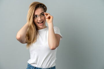 Fototapeta premium Young blonde woman in glasses on a gray background. Young girl posing on a background of a gray wall