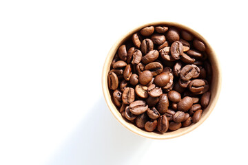 Roasted coffee beans in a kraft paper cup. Top view, copy space