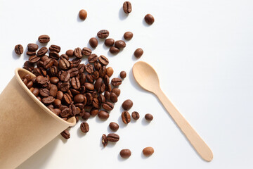 Flat lay composition with coffee beans, kraft paper cup and wooden spoon. Top view, copy space