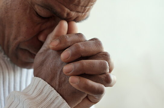 man praying to god with hands together Caribbean man praying with white background stock photo