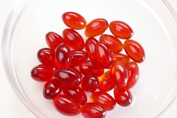Krill oil capsules. Red  capsules with krill oil in a glass transparent cup on a white...