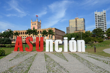 Asuncion sign in front of the Government Palace in colonial style. Park with trees and downtown...