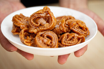 hands serving a plate of Chebakia a Moroccan pastry - Moroccan cookie famously associated with Ramadan and special occasions