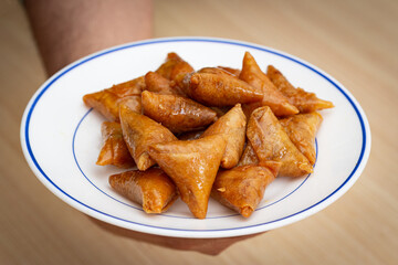 hands serving a plate of briwat ( briouat ) a Moroccan pastry - briwat is a sweet puff pastry associated with Ramadan and special occasions