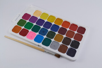 A palette of welded paint with a brush lying next to it for painting. Artistic concept. Drawing tools