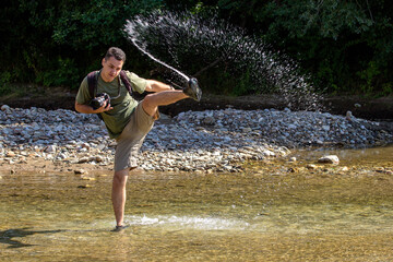 A young man dancing on the water on a sunny day, on a mountain river. © NAIL BATTALOV