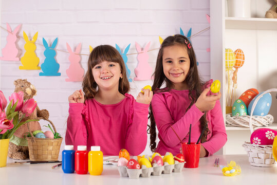 Happy Easter! Two cute little creative girls are painting eggs  hare getting ready for holiday
