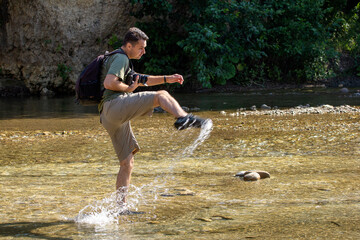 A young man dancing on the water on a sunny day, on a mountain river. © NAIL BATTALOV