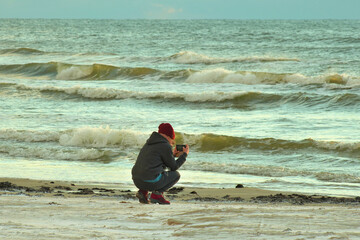 Fototapeta na wymiar The girl photographs the seascape on a smartphone.