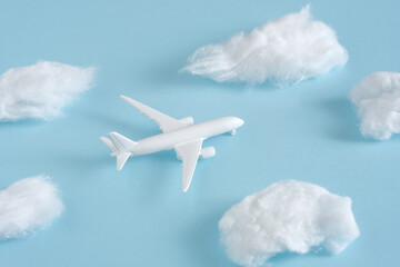 Fototapeta na wymiar White jet airplane flying between the fluffy clouds. Travel around the world creative concept