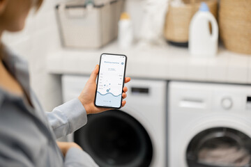 Woman controls washing machine with a smartphone