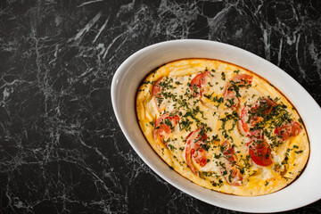 Omelet with tomatoes and cheese for breakfast in a white dish