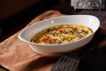 Omelet with tomatoes and cheese for breakfast in a white dish