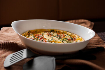 Omelet with tomatoes and cheese for breakfast in a white dish