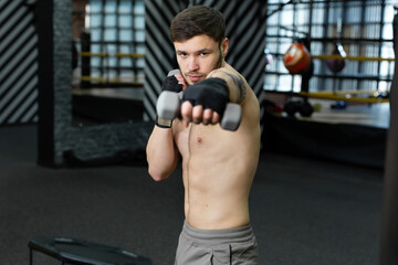 Fototapeta na wymiar Kickboxer does a circular workout with dumbbells in the gym