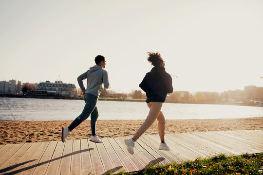 Load on the heart cardio system. Outdoor sports activities. A man and a woman run along the embankment in the city. A couple in love together. Training in a park in the city center. Healthy lifestyle.