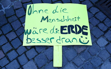 Demoschild auf Kopfsteinpflaster: "Ohne die Menschheit wäre die Erde besser dran"