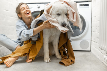 Woman with dog having fun in the laundry room at home