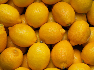 The background of bright ripe, yellow lemons in full screen. The texture of greenhouse fruits in the window of the market, store.  Top view, close-up, food wallpaper. The concept of harvesting.