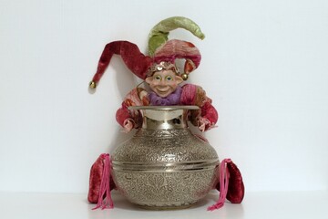 buffoon toy holding silver shining jug on white background