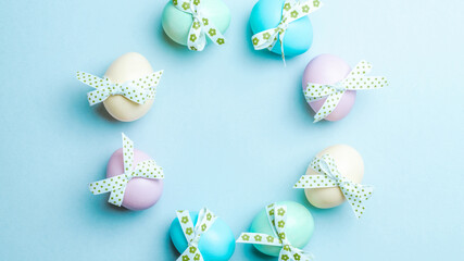 Easter flat. Colorful egg with tape ribbon on pastel blue background in Happy Easter decoration. Spring holiday top view concept.