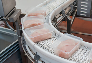Food products meat chicken in plastic packaging on the conveyor.Factory for the production of food from meat.Meat processing equipment.Production line with packaging and cutting of meat.